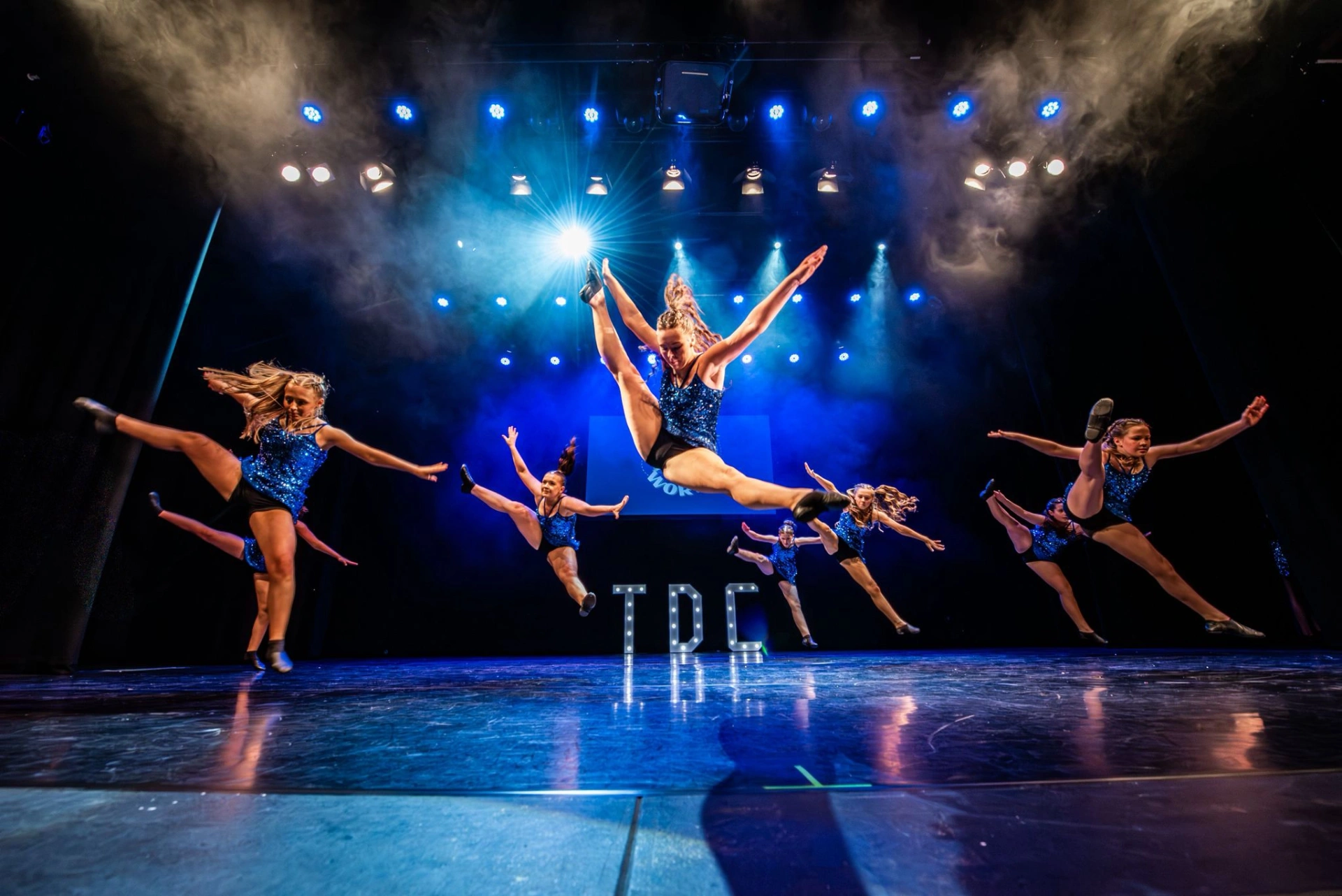 TDC dancers on stage with hands raised